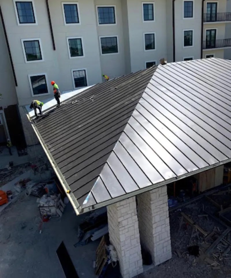 Crew installing standing seam metal roof panels on a commercial project in Woodbury